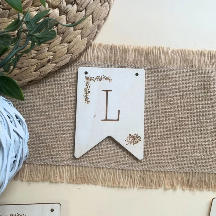 Tabliczka ze sklejki, grawer z literą L i delikatnym roślinnym detalem, element girlandy.