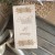 Drewniane pudełko na pieniądze z personalizowanym grawerem imienia i wieku, ze wstążką.