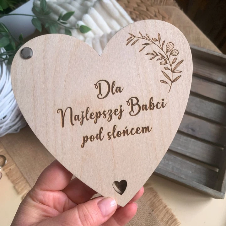 Zbliżenie na dwuwarstwowe serce z drewna o grubości 6mm, widoczny grawer Dla najlepszej Babci pod słońcem oraz personalizowane życzenia od wnuków.