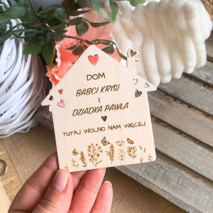 Drewniany magnes w kształcie domku z grawerowanym motywem roślinnym i personalizowanym tekstem dla babci i dziadka.