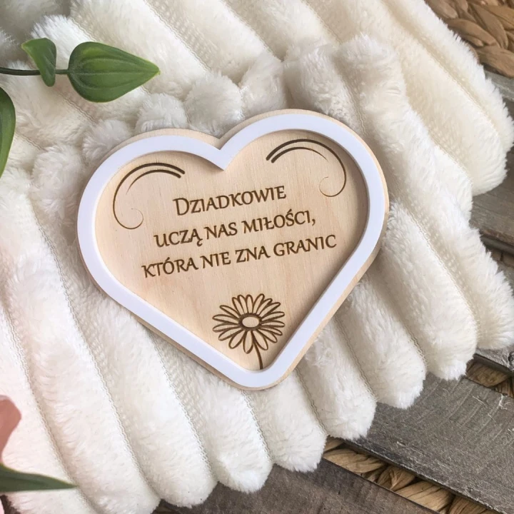 Personalizowany prezent na Dzień Babci i Dziadka - drewniany magnes serce z białą ramką pleksi i grawerowaną stokrotką.