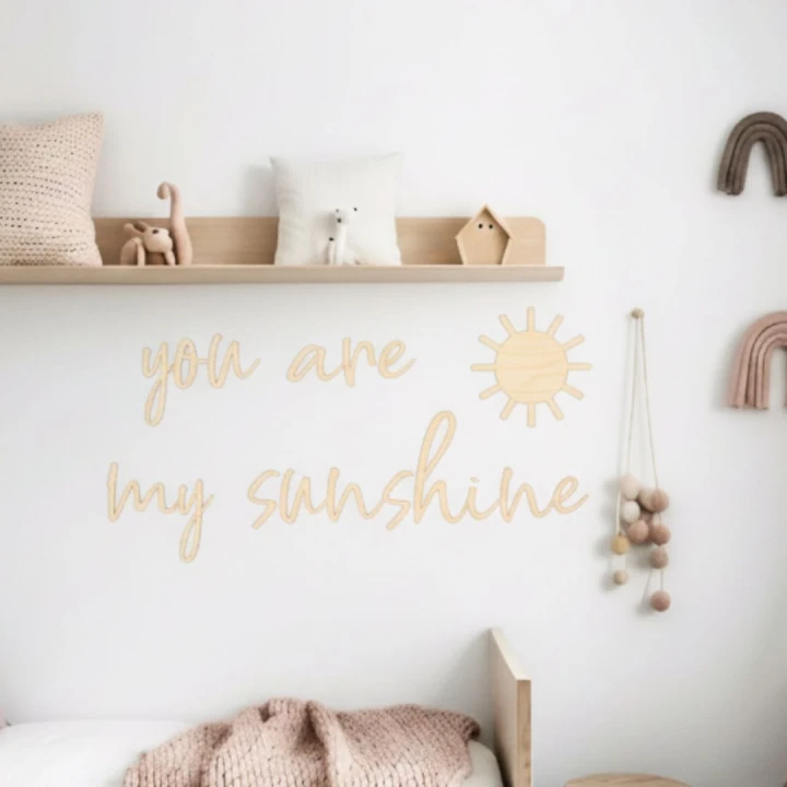 Aranżacja pokoju dziecka w stylu skandynawskim z drewnianym napisem You are my sunshine na ścianie nad łóżkiem