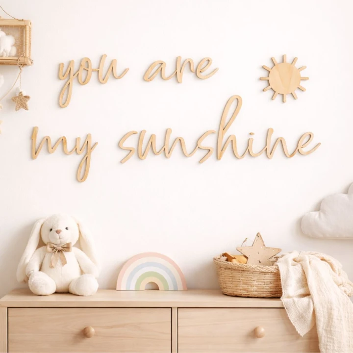 drewniany napis „you are my sunshine” z dekoracyjnym słoneczkiem na ścianie nad drewnianą komodą