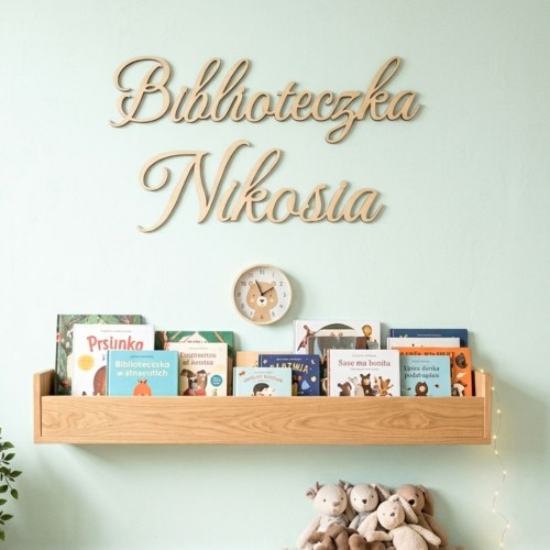 Personalizowany napis ze sklejki Biblioteczka Majki na gładkiej ścianie nad półką z książkami dla dzieci.