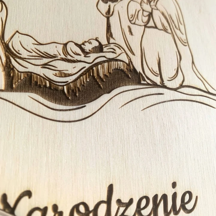 Zbliżenie na precyzyjny grawer motywu Szopki Bożonarodzeniowej na drewnianej okładce albumu, pamiątka świąteczna.
