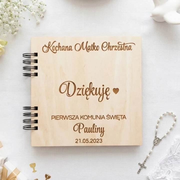 Drewniany album na zdjęcia z Pierwszej Komunii Świętej. Na okładce grawerowany napis „Kochana Matko Chrzestna dziękuję” oraz imię dziecka i data.